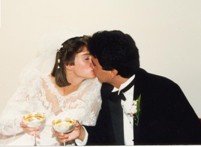 Bride and groom kissing, holding glasses