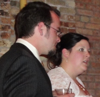 Two people in formal attire at brick wall
