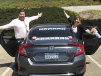 Two people posing by car with open doors
